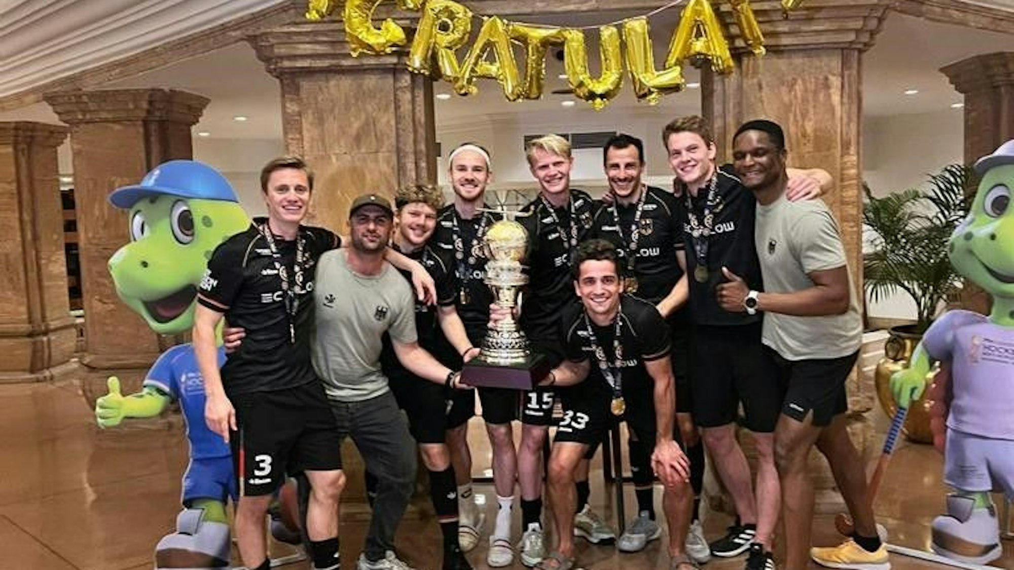 Die Kölner Weltmeister-Helden um (v.l.) Mats Grambusch, Pasha Gademan, Thies Prinz, Christopher Rühr, Tom Grambusch, Moritz Trompertz, Timur Oruz, Jean Danneberg und Mannschaftsarzt Philip Ibe feiern im Mannschaftshotel in Indien den WM-Titel.