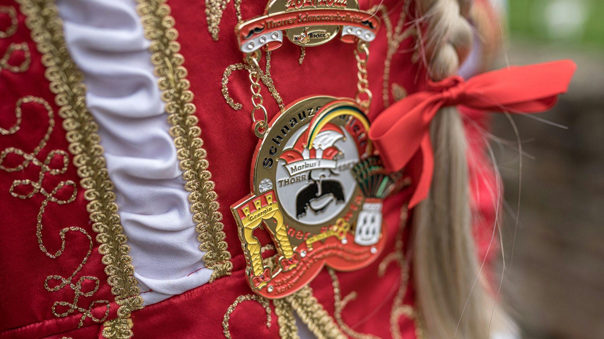 Der Orden des Thorrer Dreigestirns zeigt einen schwarzen Walross-Schnäuzer über breit lächelndem Mund.