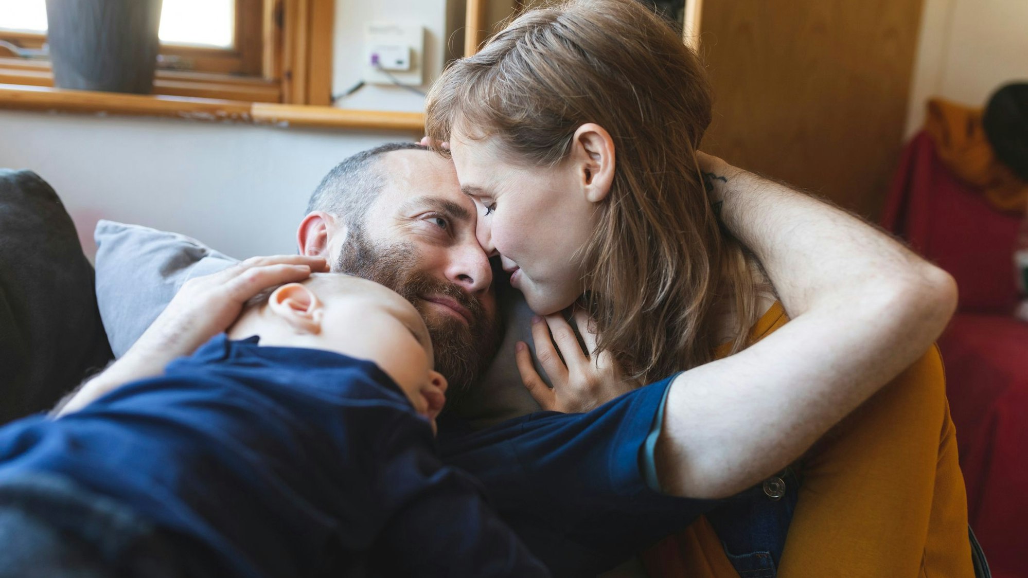 Ein Paar kuschelt, während ihr Baby schläft.