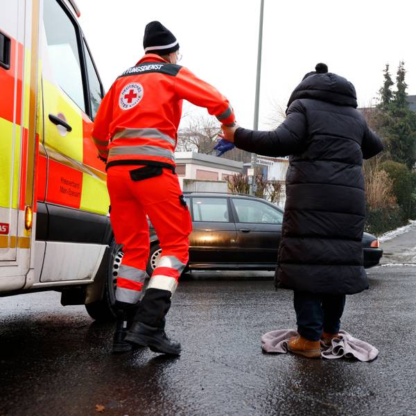 Der Rettungsdienst hilft einer Dame bei Glätte über die Straße.