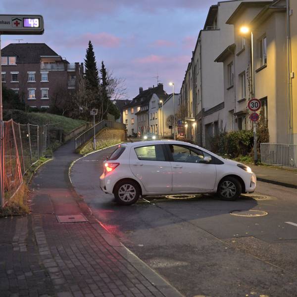 Ein weißer Kleinwagen steht quer auf der Straße vor dem Parkhaus des Bergisch Gladbacher Marienkrankenhauses.