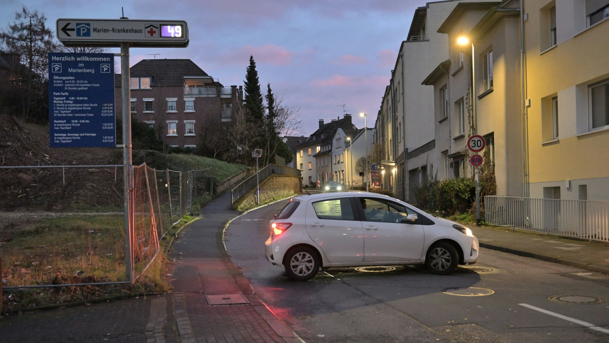 Ein weißer Kleinwagen steht quer auf der Straße vor dem Parkhaus des Bergisch Gladbacher Marienkrankenhauses.