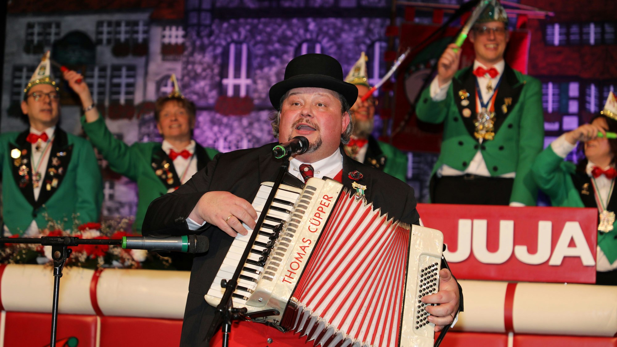 Thomas Cüpper steht mit Akkordeon auf einer Bühne.