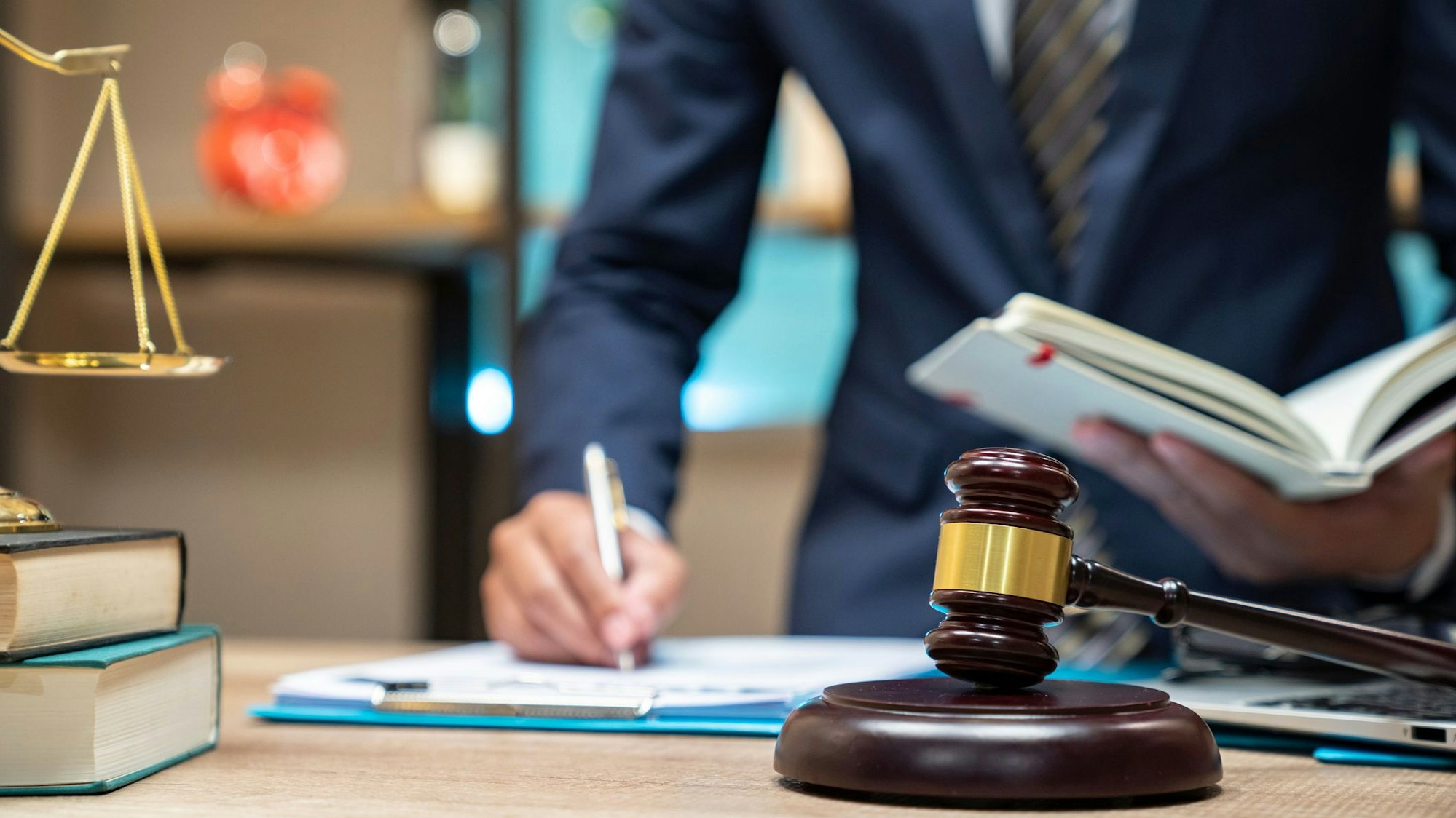 Ein Anwalt liest ein Gesetzesbuch und macht sich dabei Notizen. (Symbolfoto)