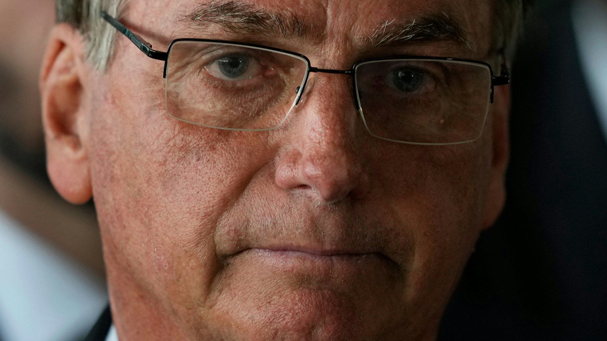 Man sieht eine Nahaufnahme von Bolsonaros Gesicht, er schaut in die Kamera.