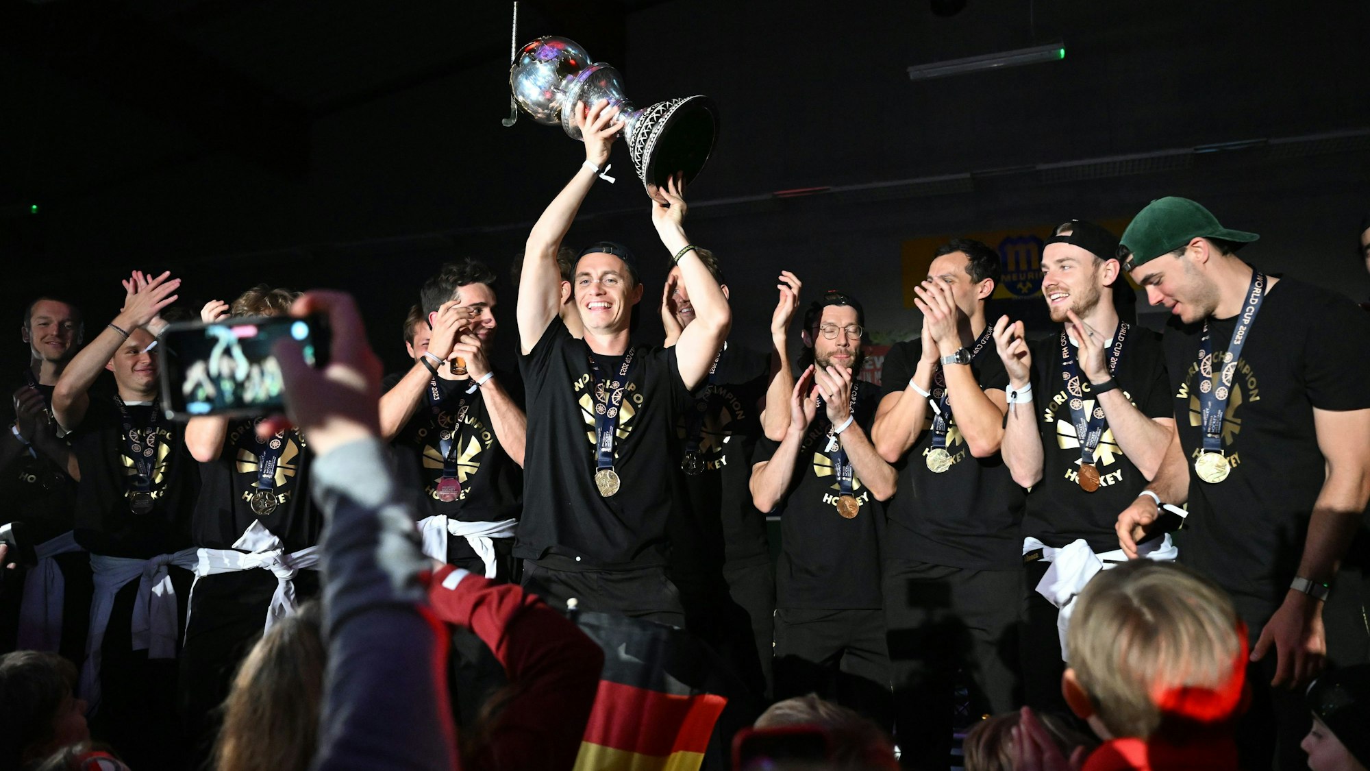 Ankunft der deutschen Nationalmannschaft nach dem WM-Triumph. Kapitän Mats Grambusch (M) hebt den Weltmeister-Pokal in die Höhe. Die Weltmeister-Mannschaft feiert mit den Fans beim Kölner Tennis- und Hockey Club Rot-Weiss.