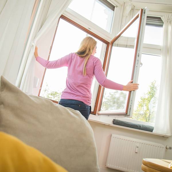 Eine Frau öffnet das Fenster, um ihre Wohnung zu lüften.