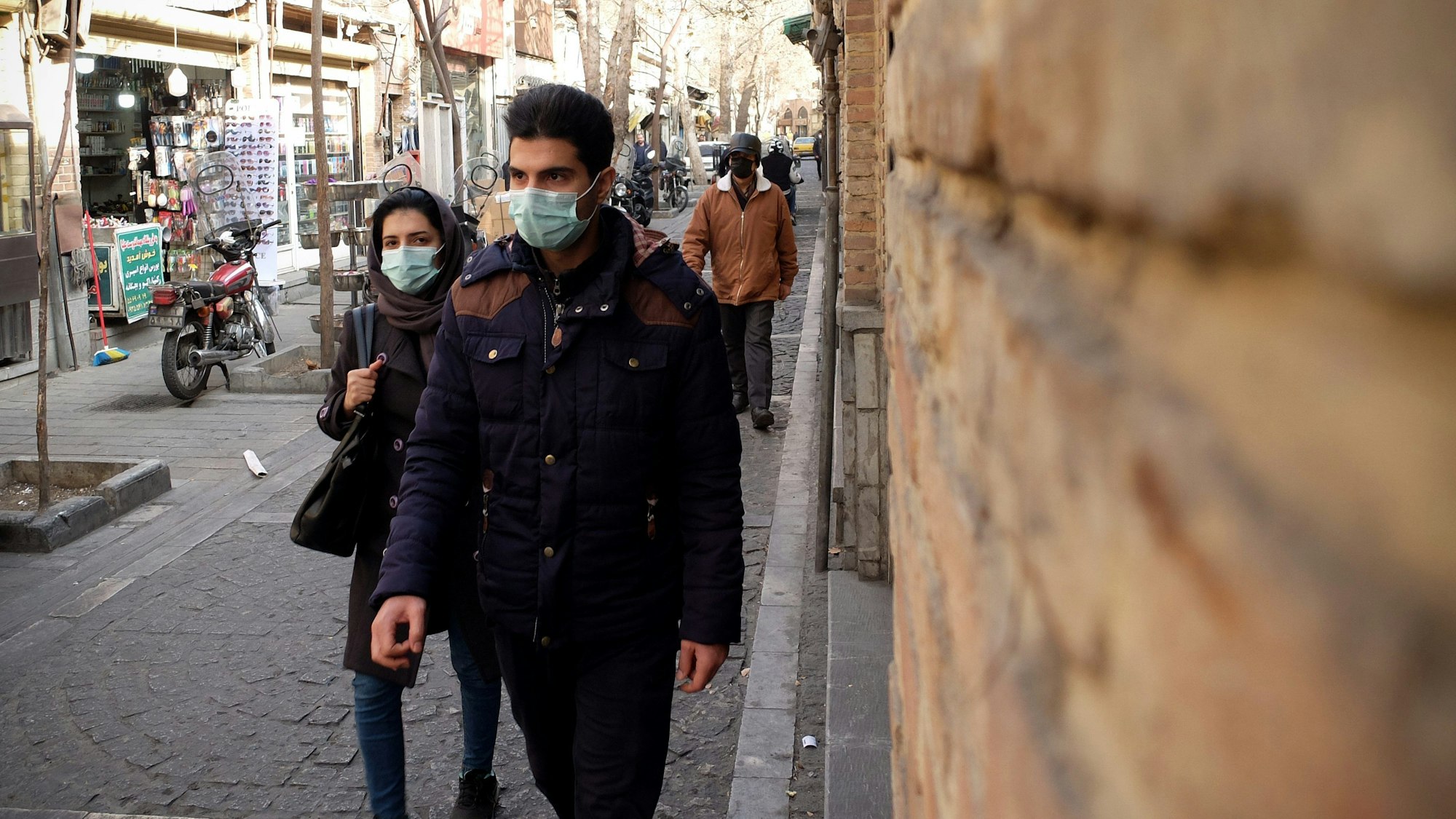 Ein iranisches Paar geht im Stadtteil Shapour im Süden Teherans die Straße entlang.