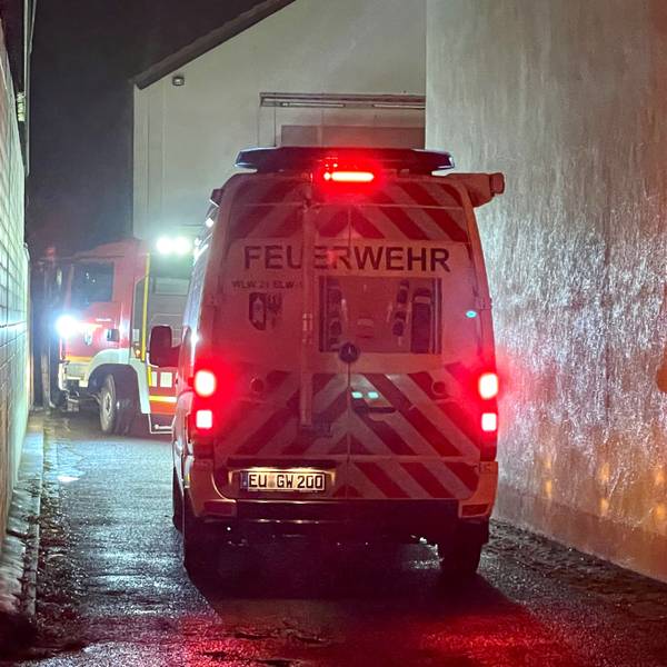 Zwei Feuerwehrfahrzeuge stehen in einer Einfahrt.