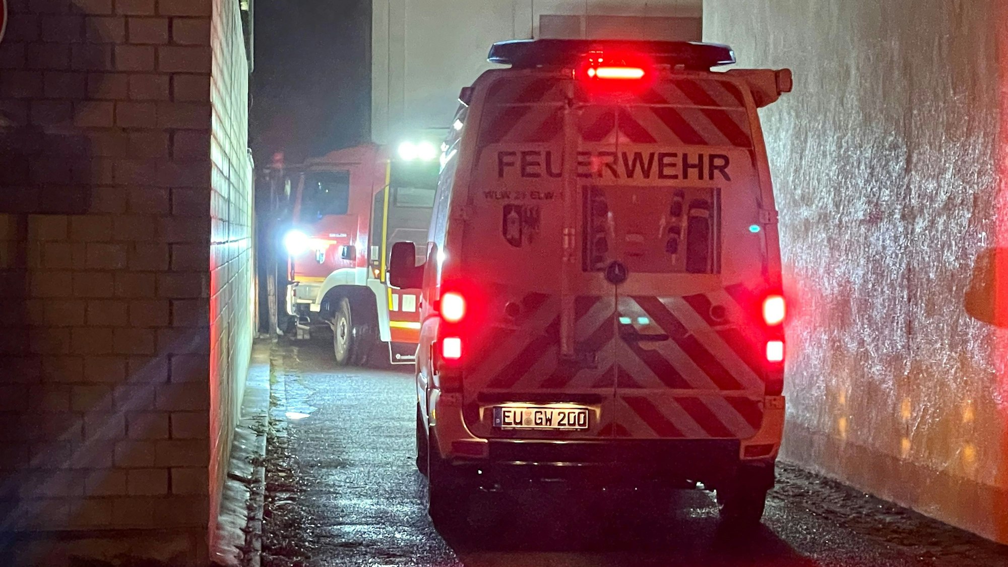 Zwei Feuerwehrfahrzeuge stehen in einer Einfahrt.