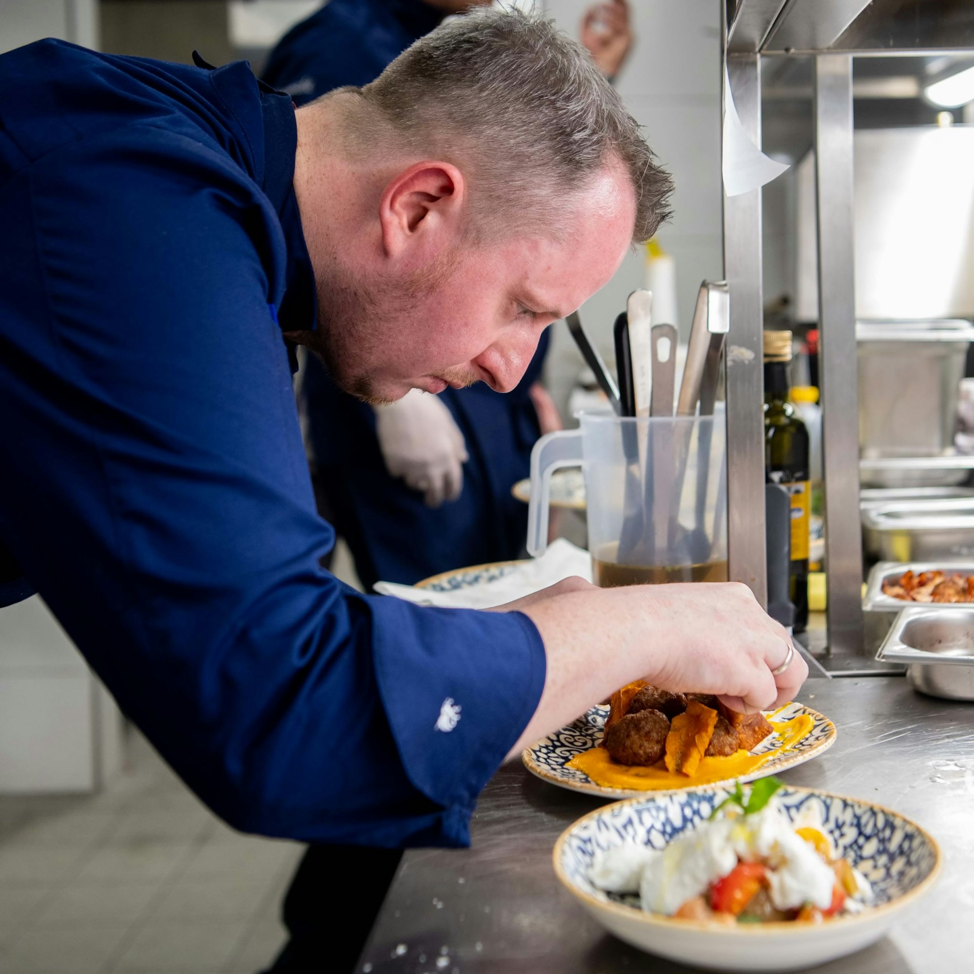 Ein Koch richtet Gerichte auf einem Teller an.