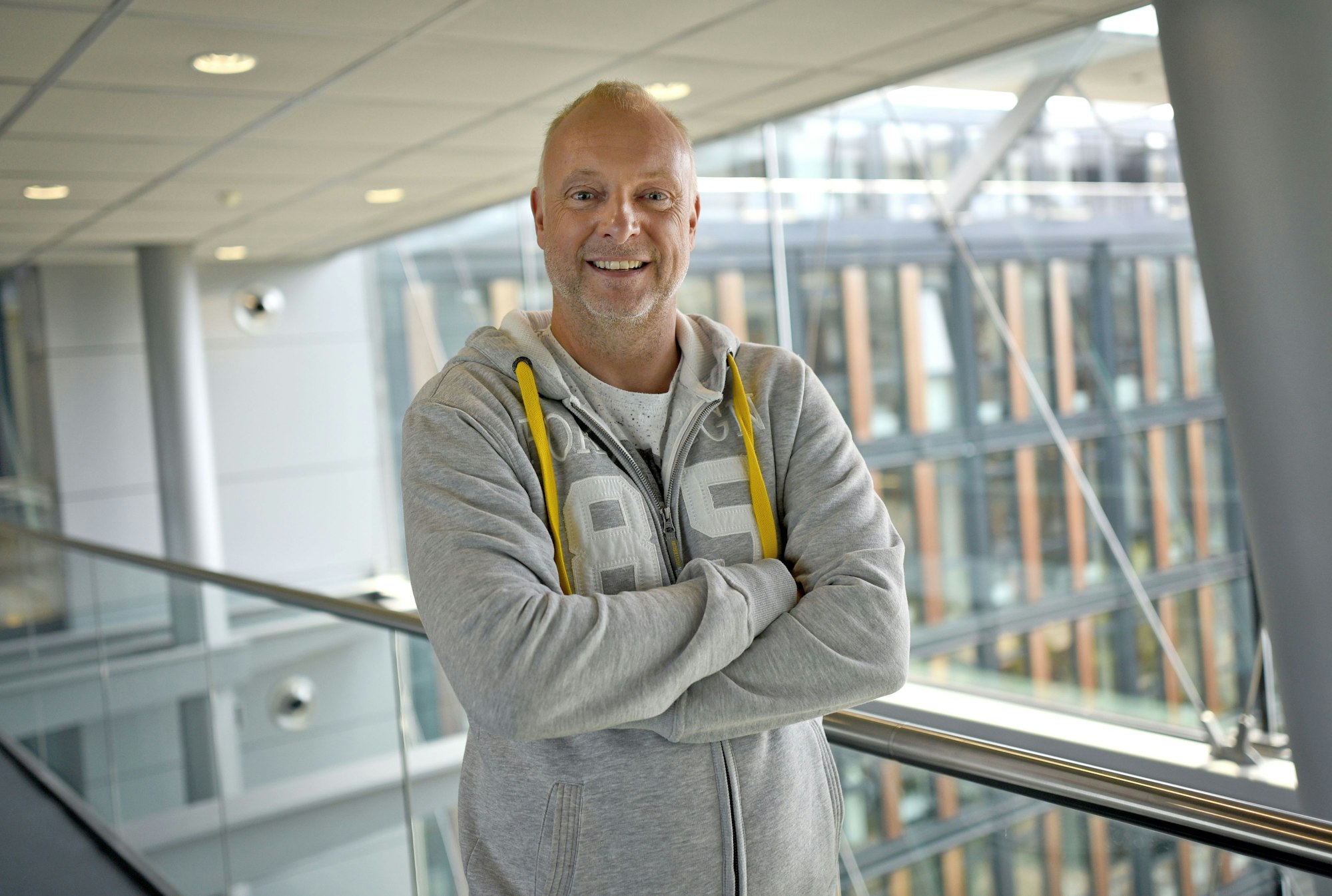 Frank Buschmann lacht in einem grauen Pullover.