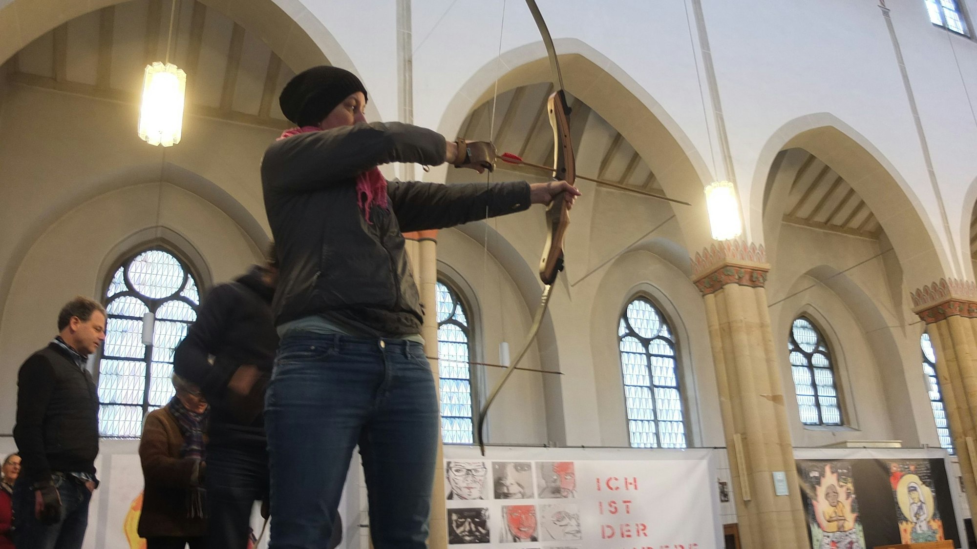 Frau, die Pfeil und Bogen in der Hand hält und auf etwas zielt