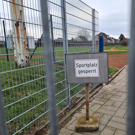 Auf dem Foto ist der Rasenplatz des Jahnstadions in Bergheim zu sehen. Auf einem Schild ist zu lesen "Sportplatz gesperrt".