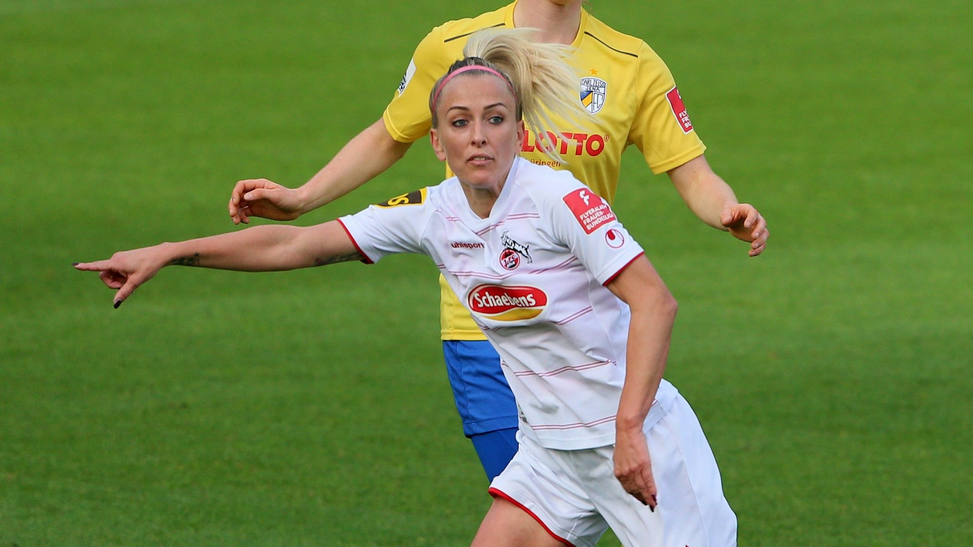 Eine Fußballspielerin zeigt mit der rechten Hand, wohin sie den Ball gespielt haben möchte.