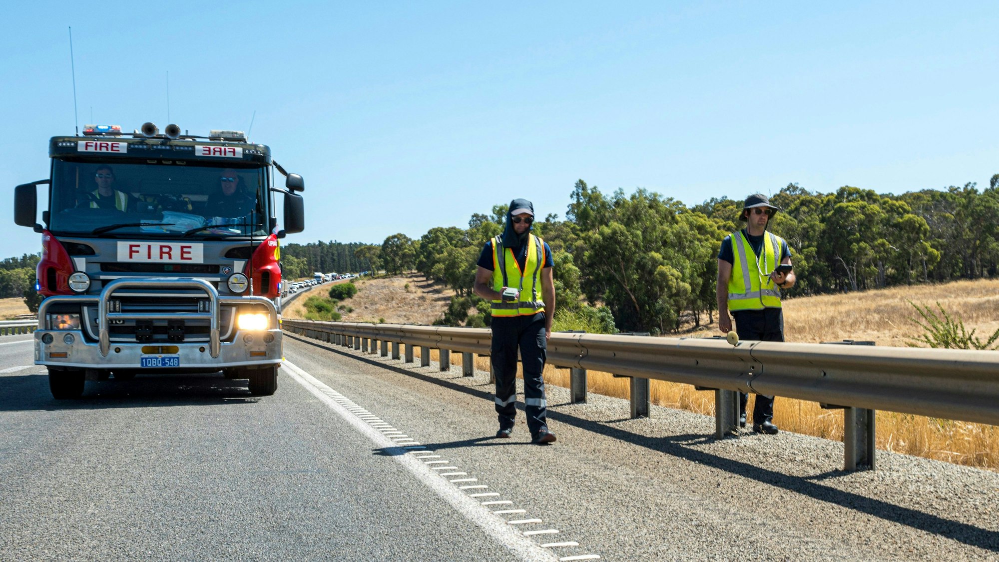 Feuerwehrleute und Strahlenschutz-Experten suchen eine Straße in Australien ab.