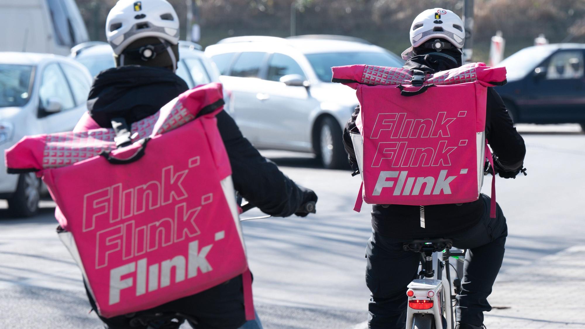 ARCHIV - 03.03.2022, Sachsen, Dresden: Zwei Fahrradkuriere tragen Rucksäcke mit dem Logo des Lebensmittel Lieferdienstes Flink. Online-Shopping und Essensbestellung im Internet boomen.