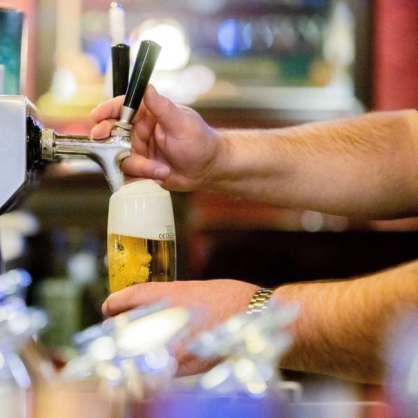 Ein Kneipenwirt zapft in einer Gaststätte Bier.