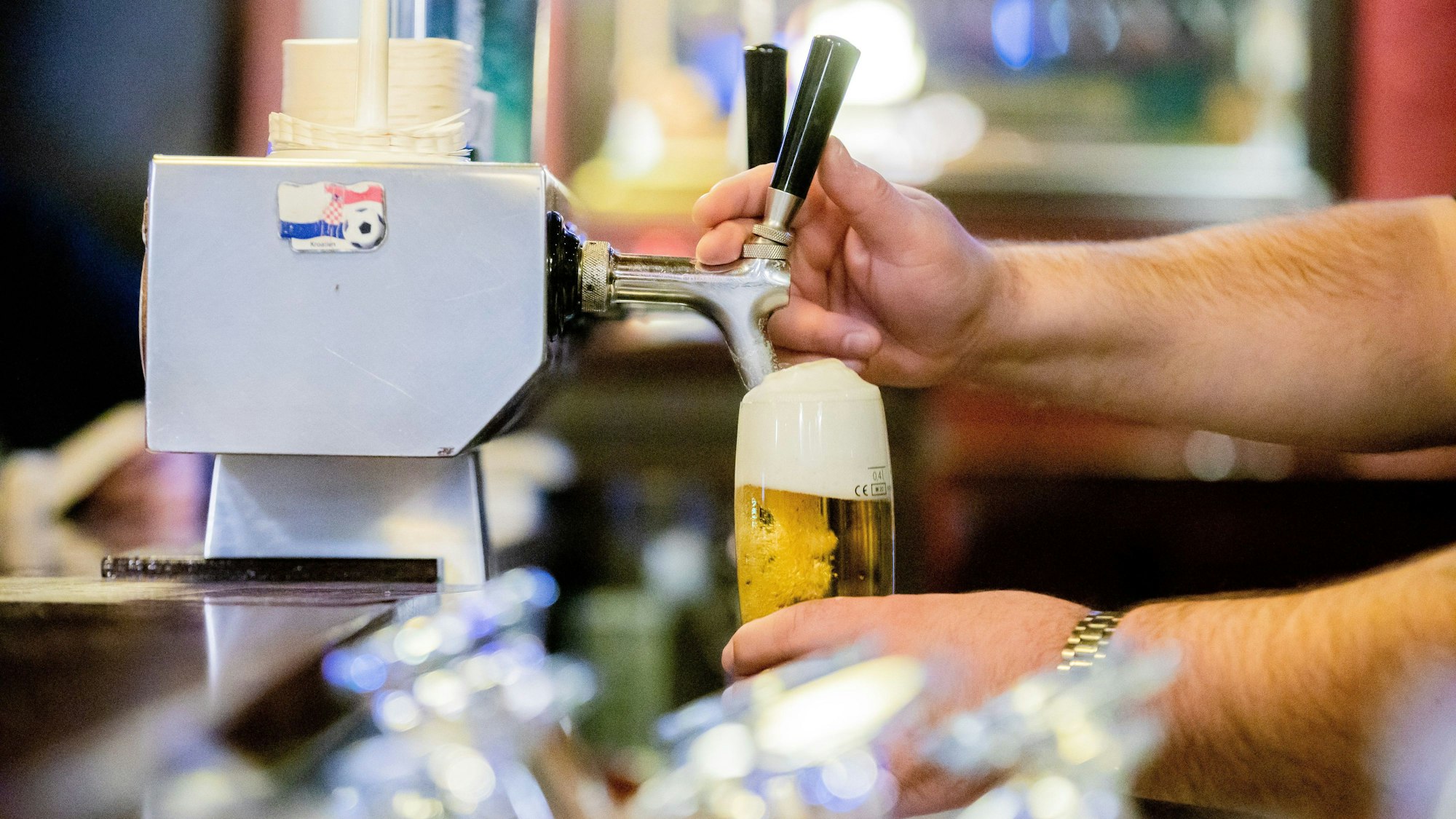 Ein Kneipenwirt zapft in einer Gaststätte Bier.