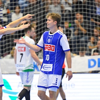Dominik Mappes, Handballspieler des VfL Gummersbach, läuft bei einem Spiel mit ausgebreiteten Fänden auf seinen Mannschaftskollegen Finn Schroven zu.