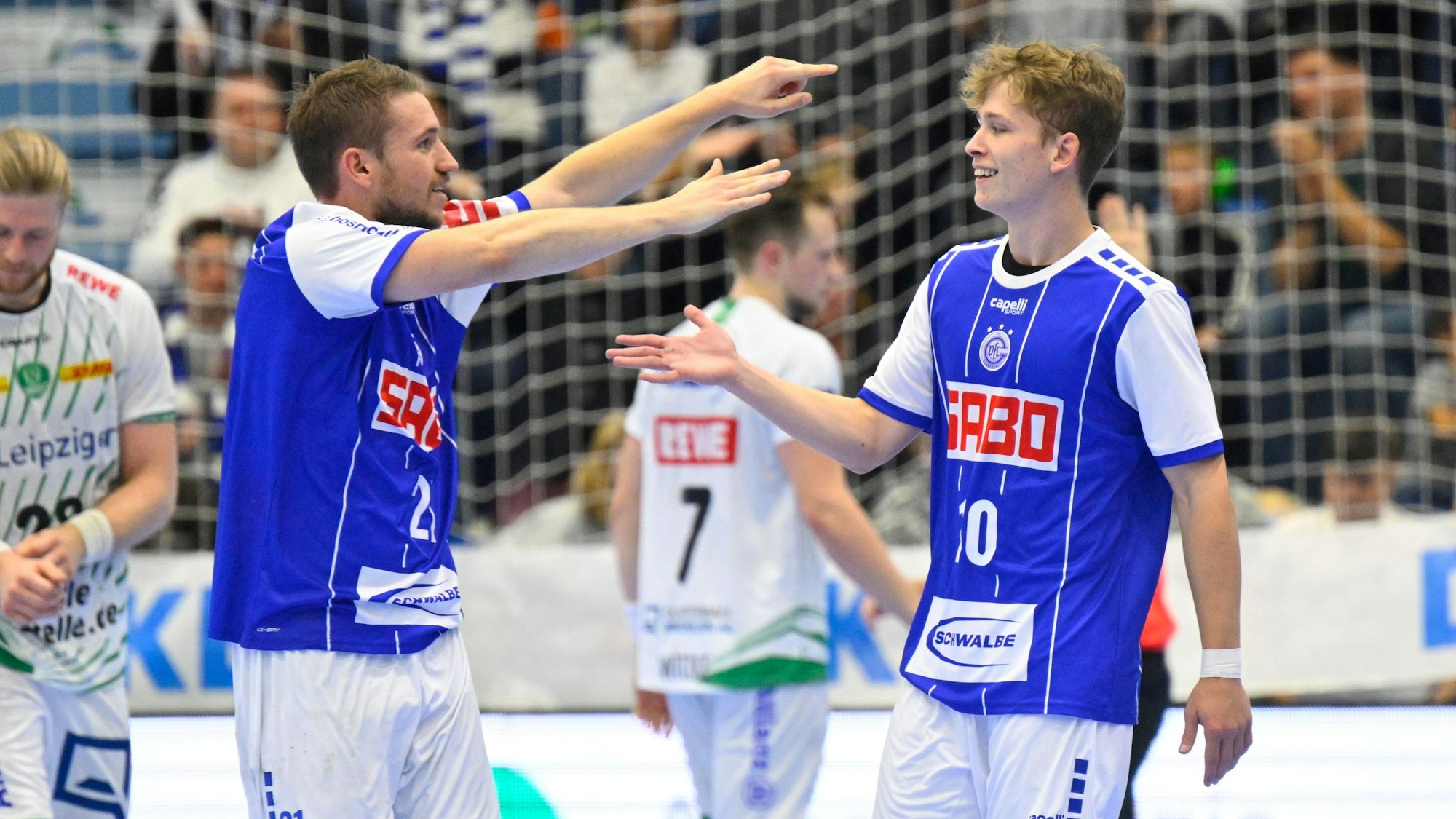 Dominik Mappes, Handballspieler des VfL Gummersbach, läuft bei einem Spiel mit ausgebreiteten Fänden auf seinen Mannschaftskollegen Finn Schroven zu.