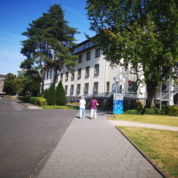Das Foto zeigt das Krankenhaus Wesseling von außen. Zwei Frauen gehen Richtung Eingang.