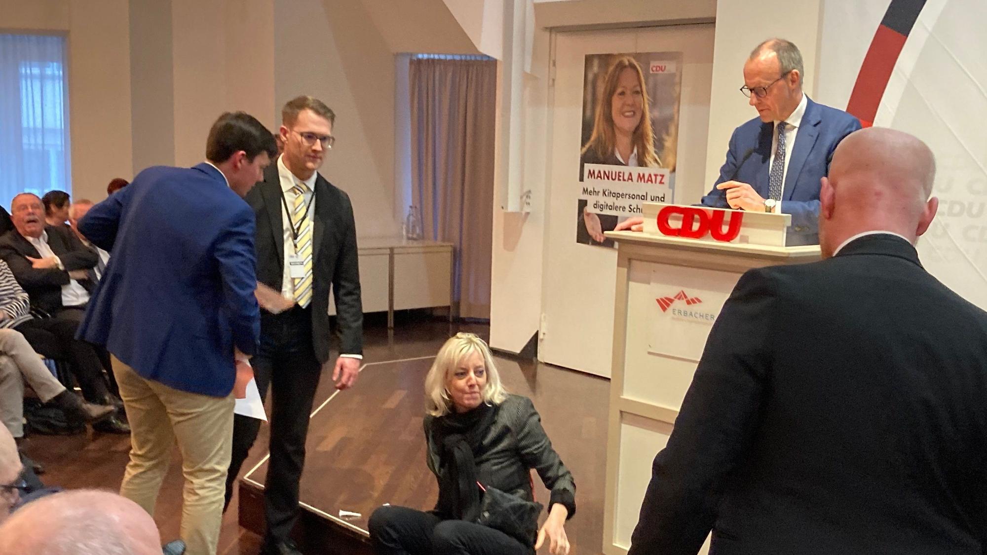 Eine von zwei Klimaschutzaktivistinnen der „Letzten Generation“ hat sich bei einer Rede des CDU-Bundesvorsitzenden Friedrich Merz (2.v.r.) auf der Bühne festgeklebt.