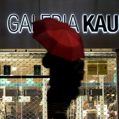 ARCHIV - 27.01.2021, Nordrhein-Westfalen, Köln: Eine Frau geht mit Regenschirm an einer geschlossenen Kaufhof Filiale vorbei.