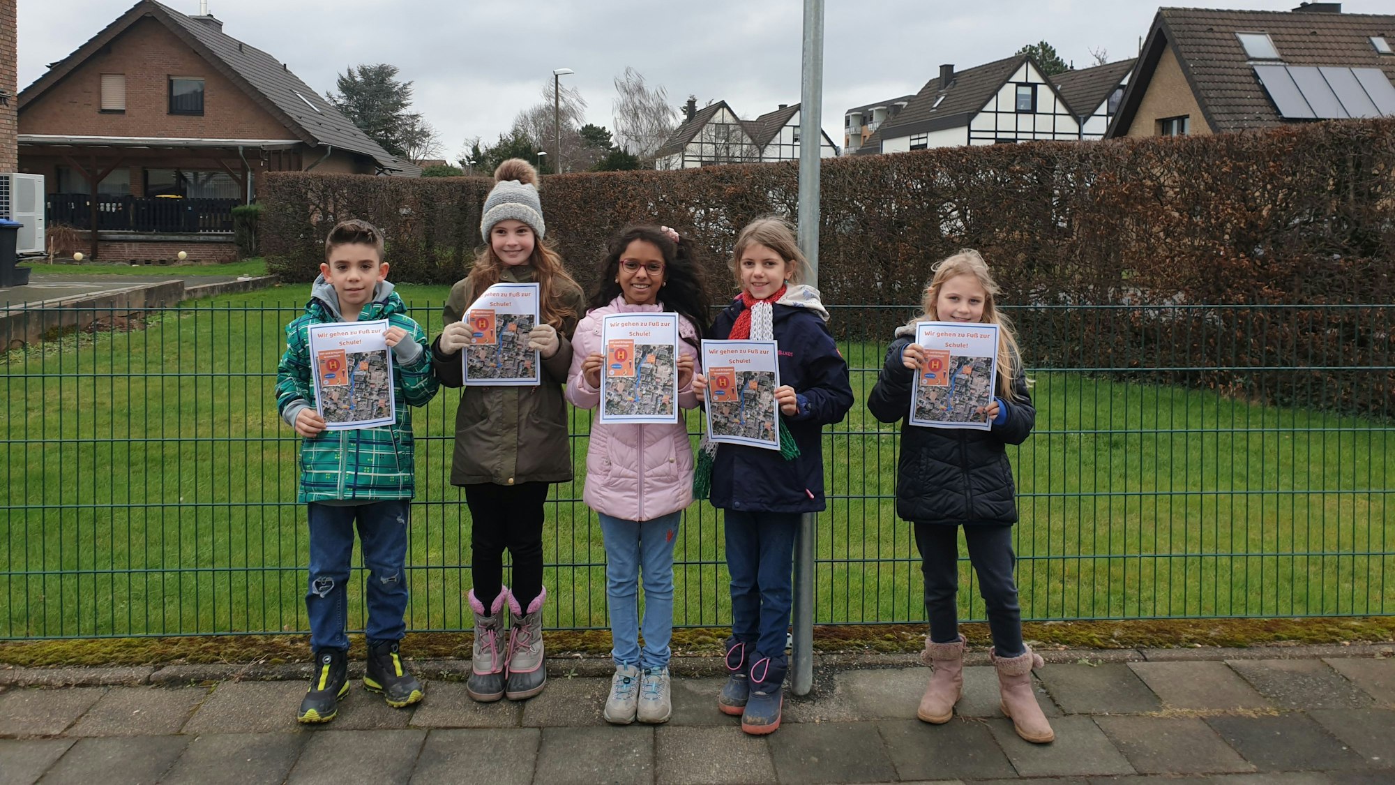 Fünf Grundschüler stehen an der Hol- und Bringzone an der Joseph-Schaeben-Schule in Weilerswist und halten jeweils ein Plakat in den den Händen.
