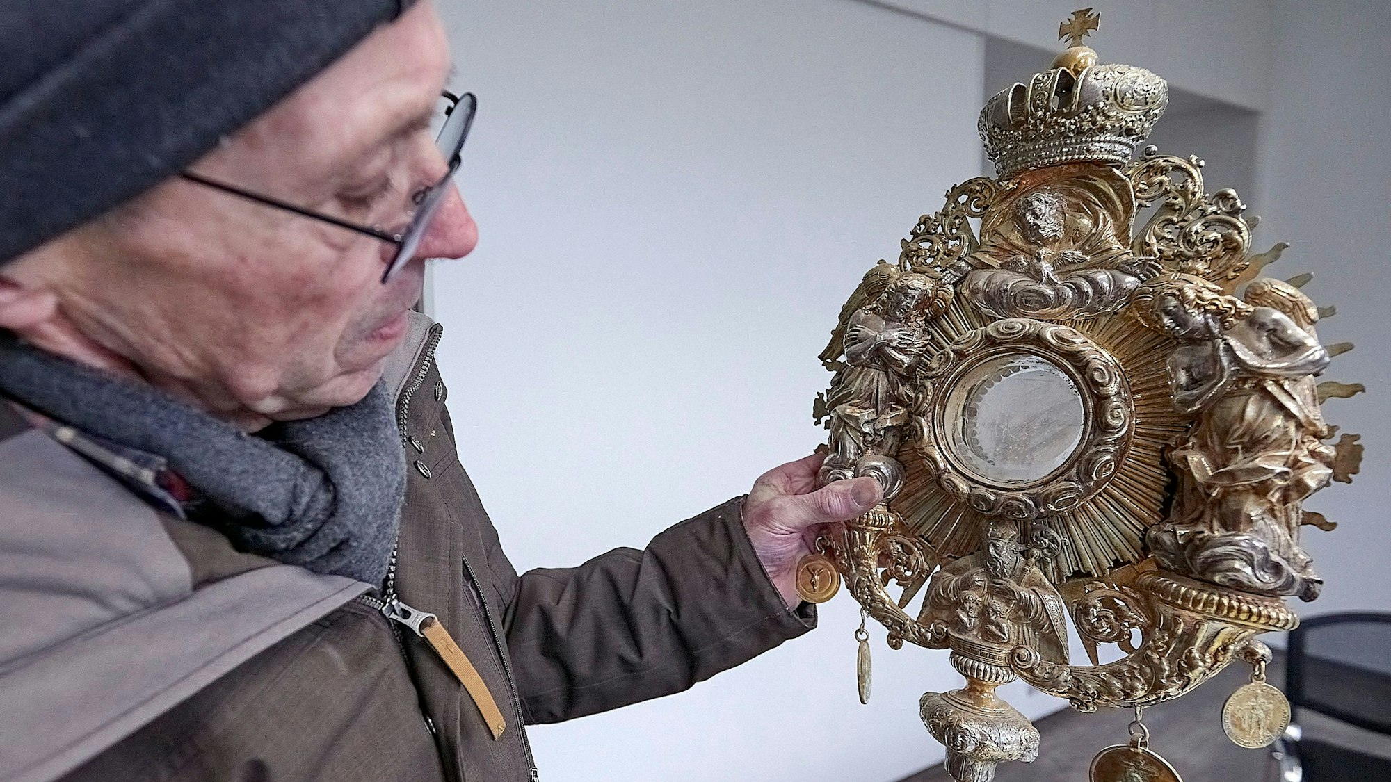 Ein Mann hält eine Monstranz, die nach der Flut von 2021 noch deutliche Schlammspuren trägt.