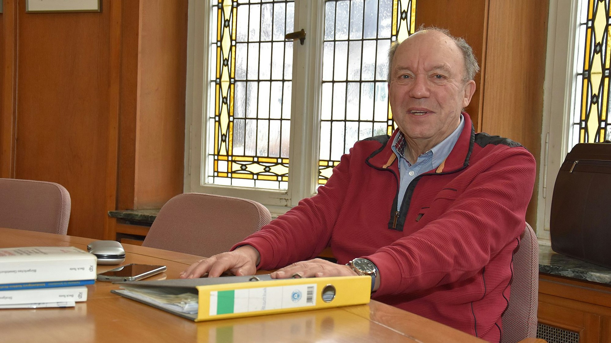 Schiedsmann Michael Ufer sitzt an einem Tisch in einem holzvertäfelten Saal.