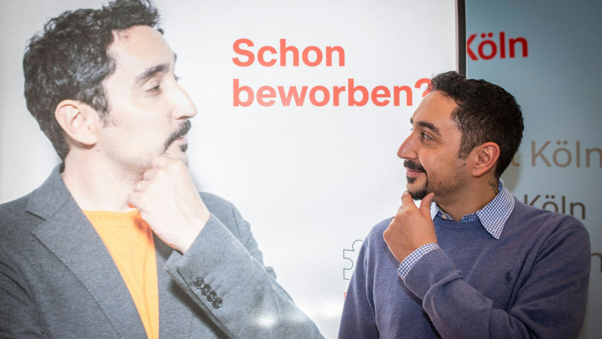 Der Rapper Eko Fresh vor einem Werbeplakat mit seinem Gesicht. Er imitiert dabei die Pose, die er auch auf dem Plakat einnimmt.