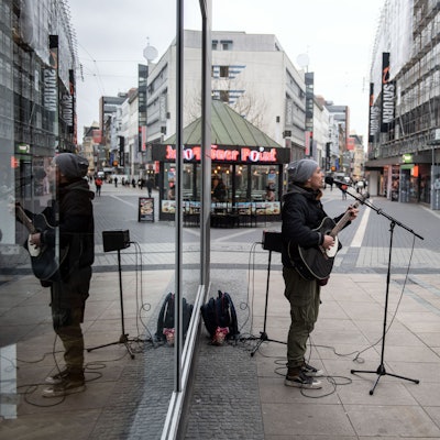 Ein Straßenmusiker spielt in der Fußgängerzone auf seiner Gitarre und singt.