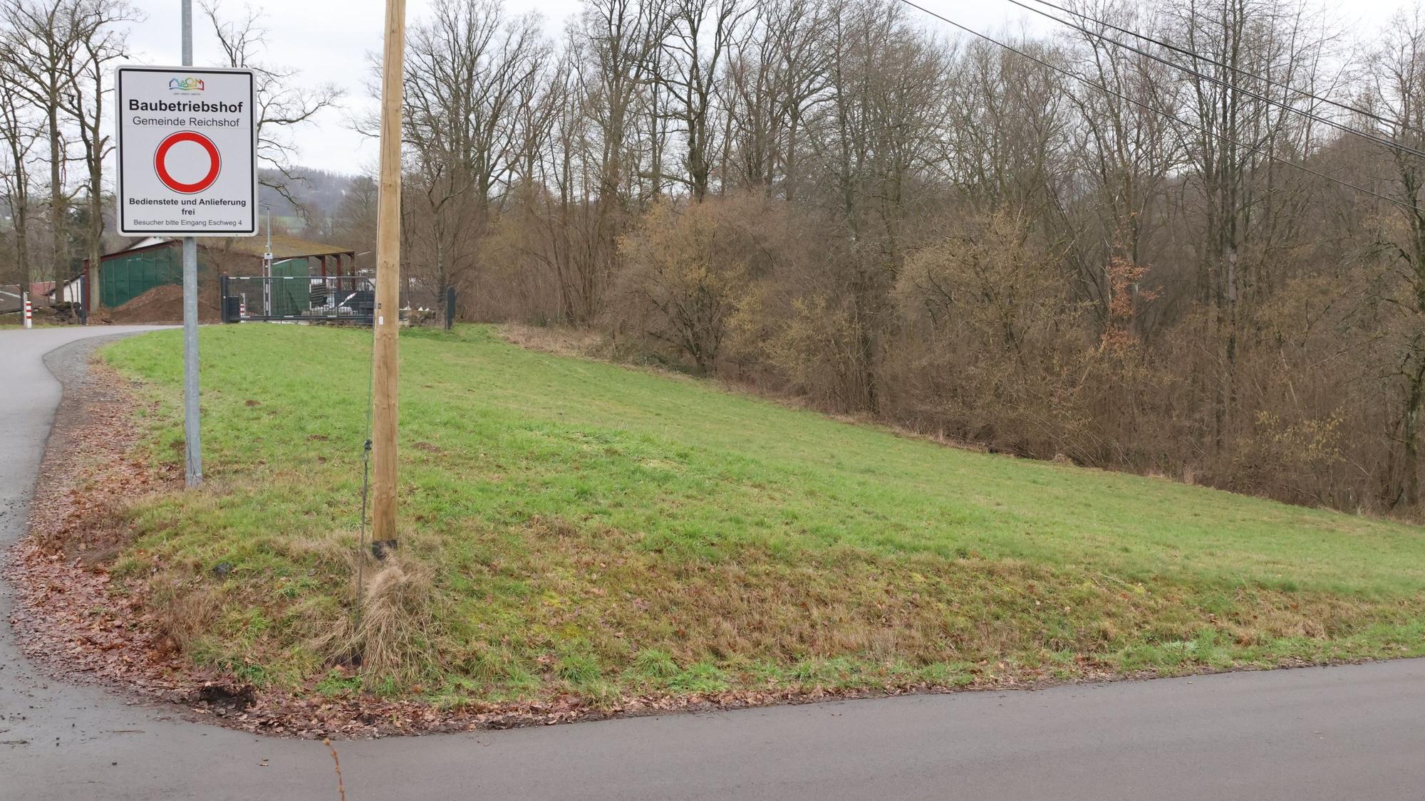 Auf einem Stück Wiese steht ein weißes Schild, auf dem ein roter Kreis zu sehen ist. Darüber steht das Wort Baubetriebshof.