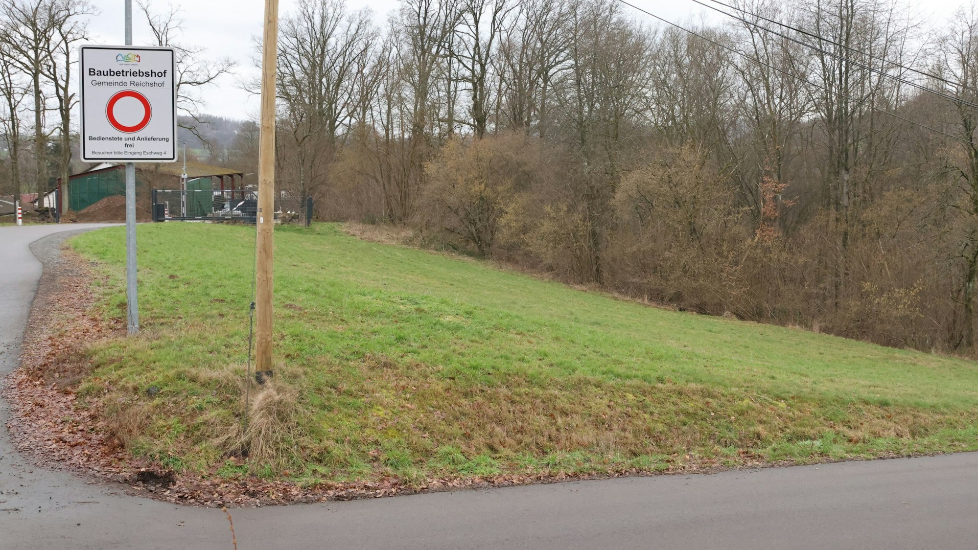 Auf einem Stück Wiese steht ein weißes Schild, auf dem ein roter Kreis zu sehen ist. Darüber steht das Wort Baubetriebshof.