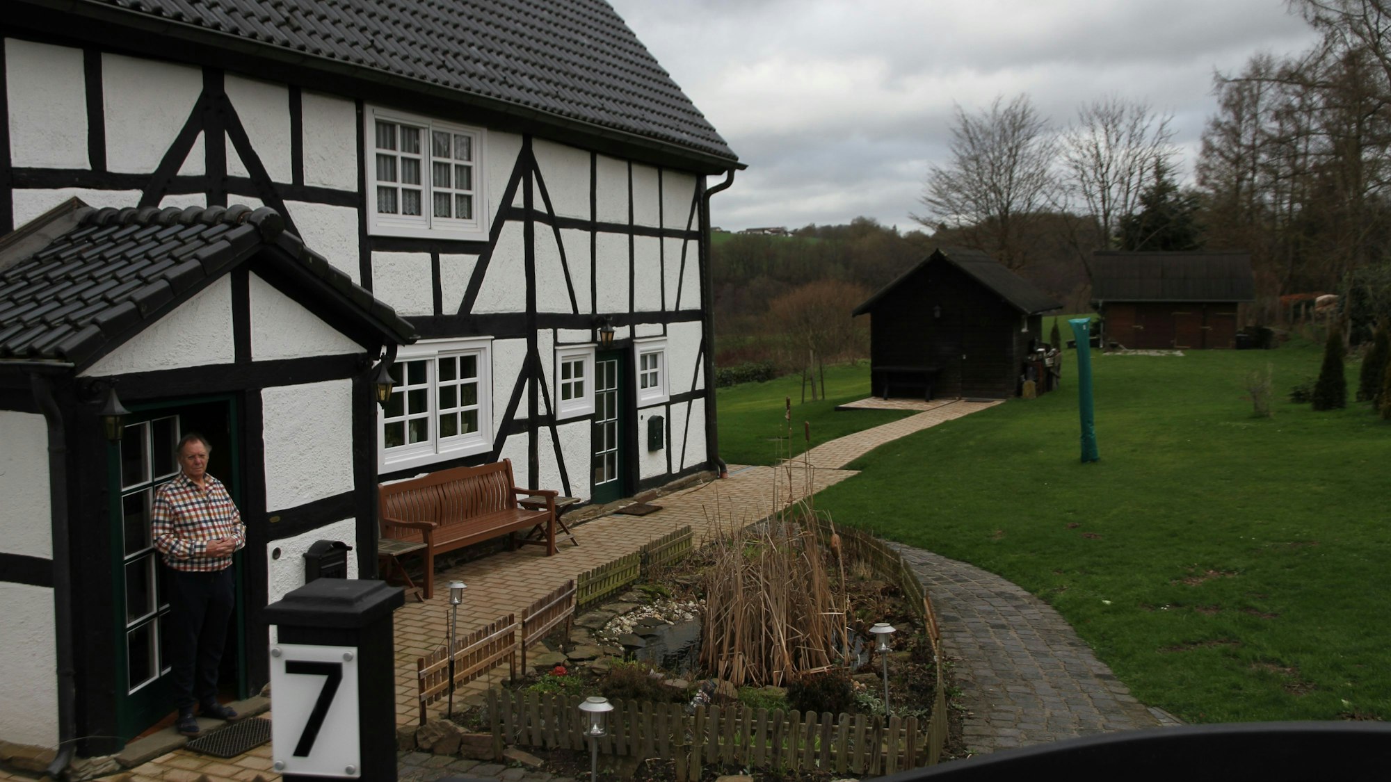 Hinter einem Fachwerkhaus liegt ein großer Garten, in der Mitte steht das Gartenhäuschen.