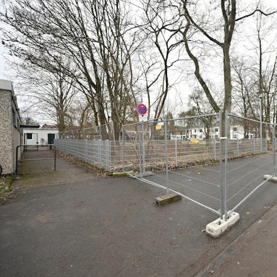 Ein Bauzaun ist um Bäume In den Auen in Bergisch Gladbach Refrath aufgebaut.