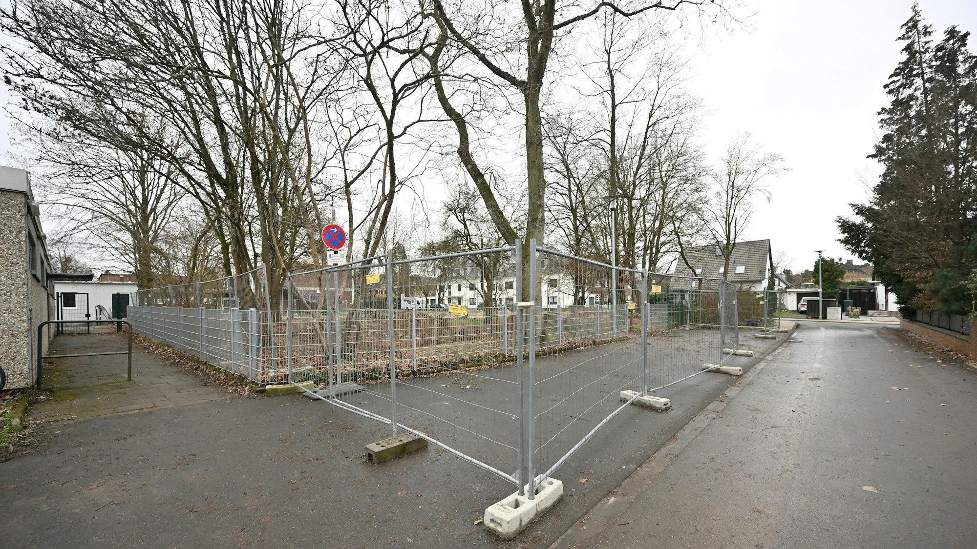 Ein Bauzaun ist um Bäume In den Auen in Bergisch Gladbach Refrath aufgebaut.