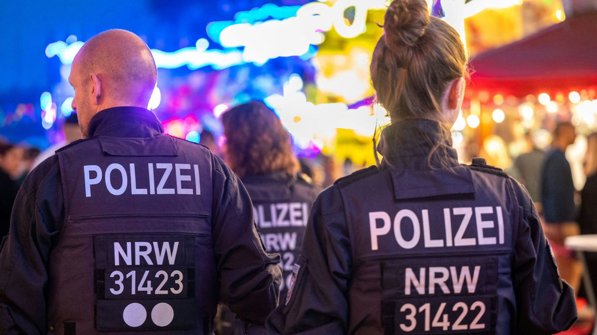 Polizistinnen und Polizisten laufen über die Deutzer Kirmes.