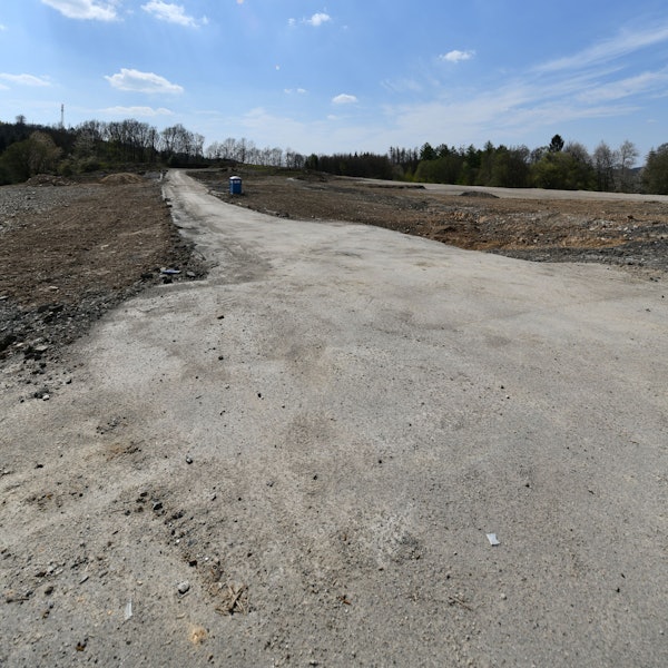 Ein braches Feld mit einem nicht-befestigten Weg und einem Dixxi-Klo