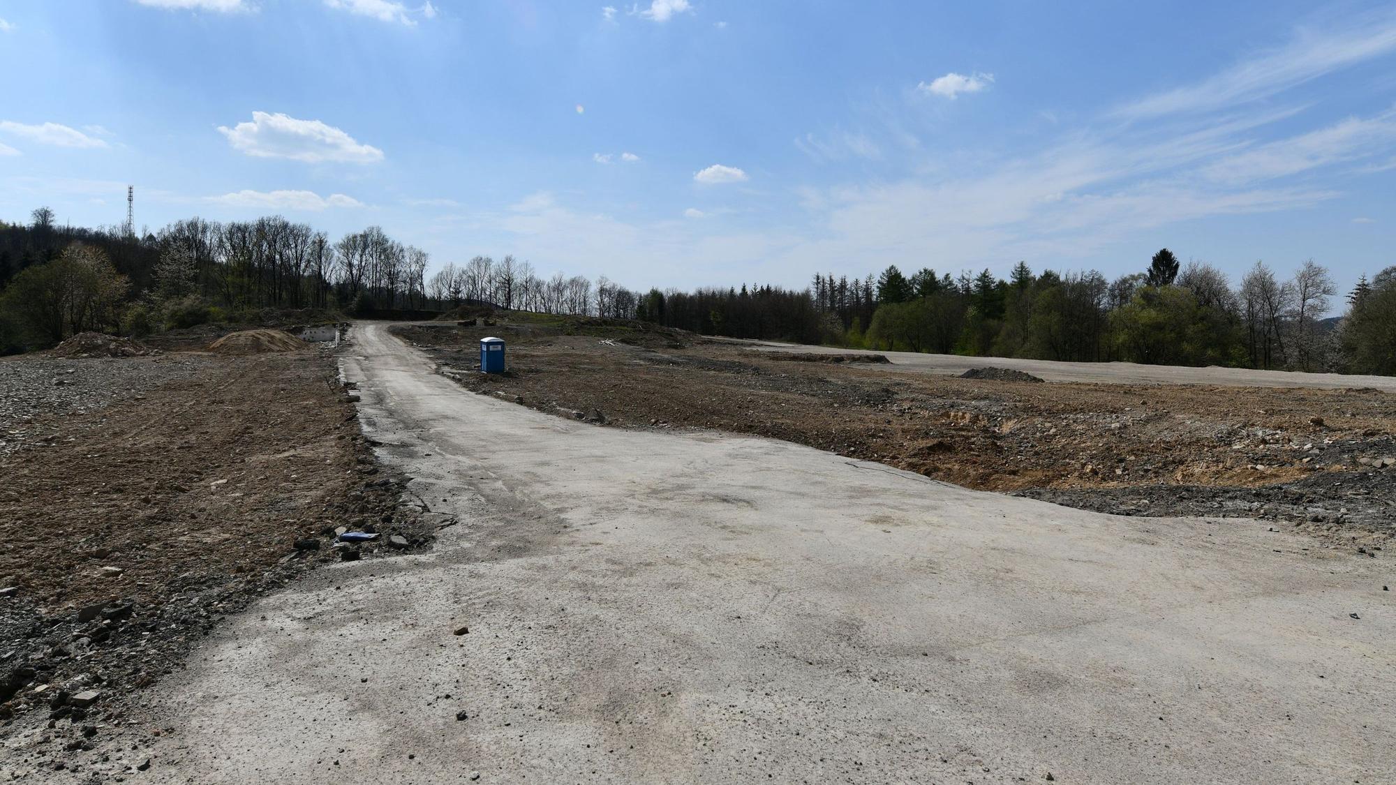 Ein braches Feld mit einem nicht-befestigten Weg und einem Dixxi-Klo
