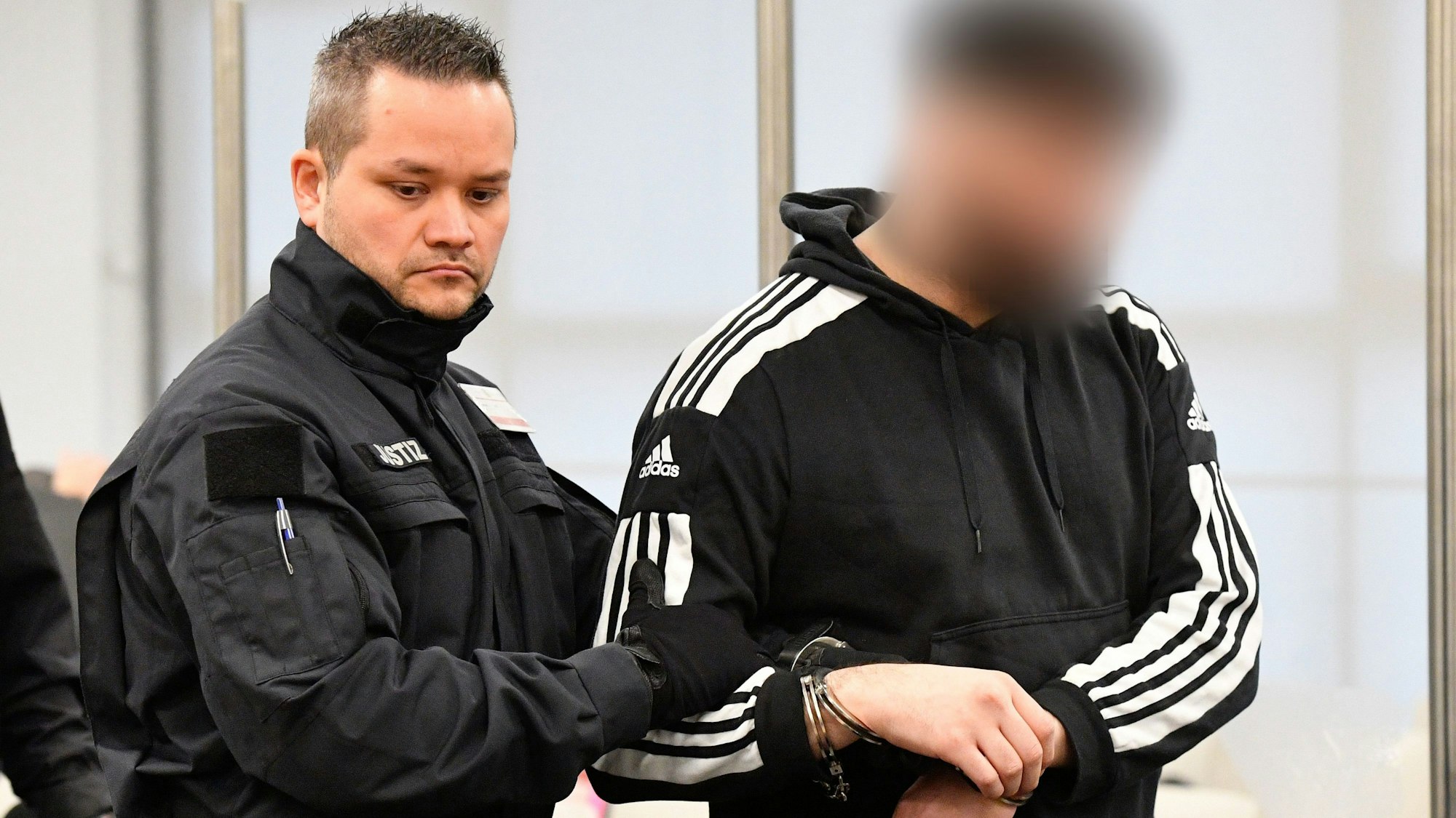 Ein Justizbeamter bringt einen Angeklagten in Handschellen in den Gerichtssaal, bevor der Prozess um einen Juwelenraub im Grünen Gewölbe des Dresdner Residenzschlosses fortgesetzt wird.