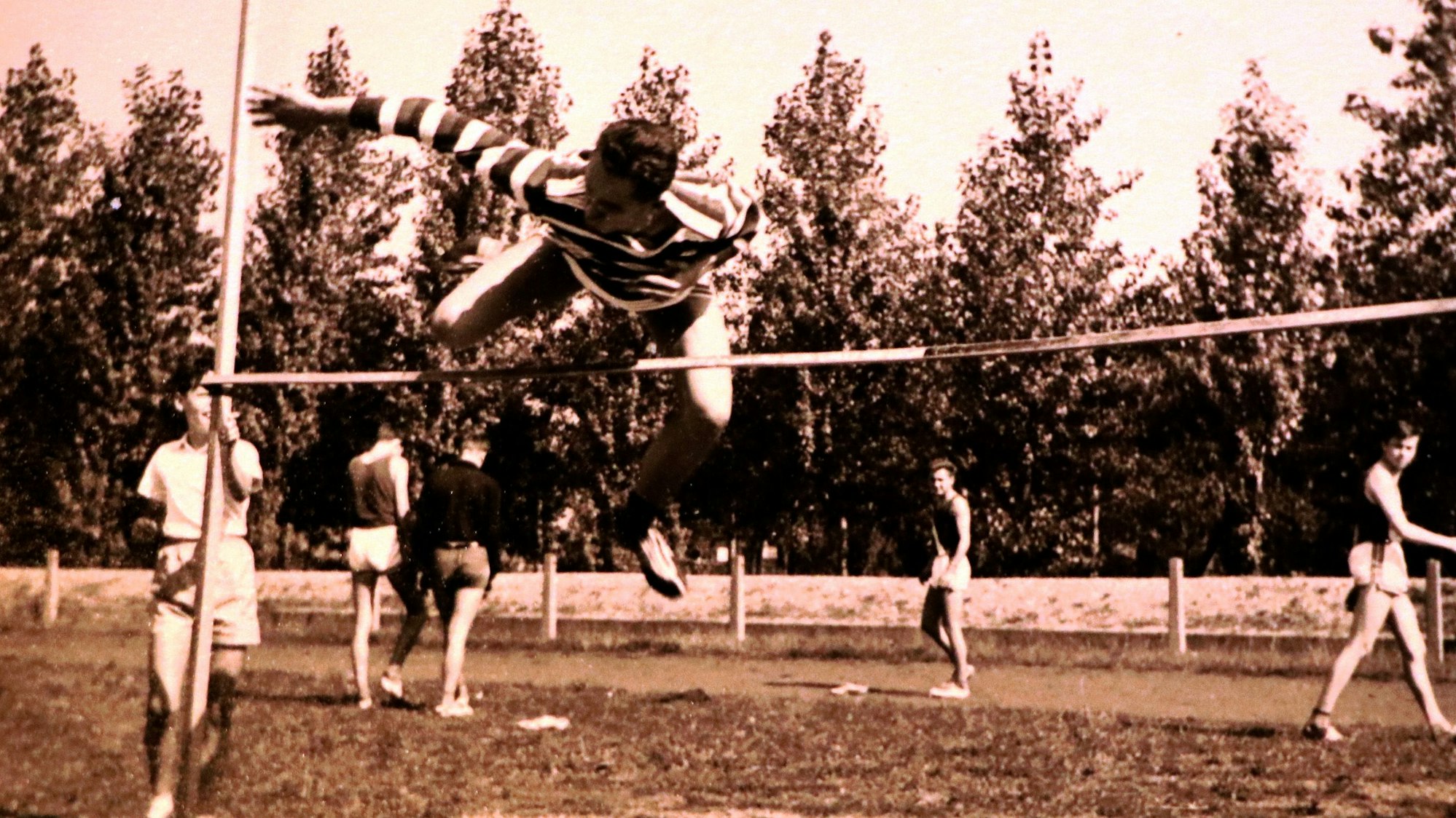 Das Foto zeigt, wie ein Athlet die Latte beim Hochsprung meistert.