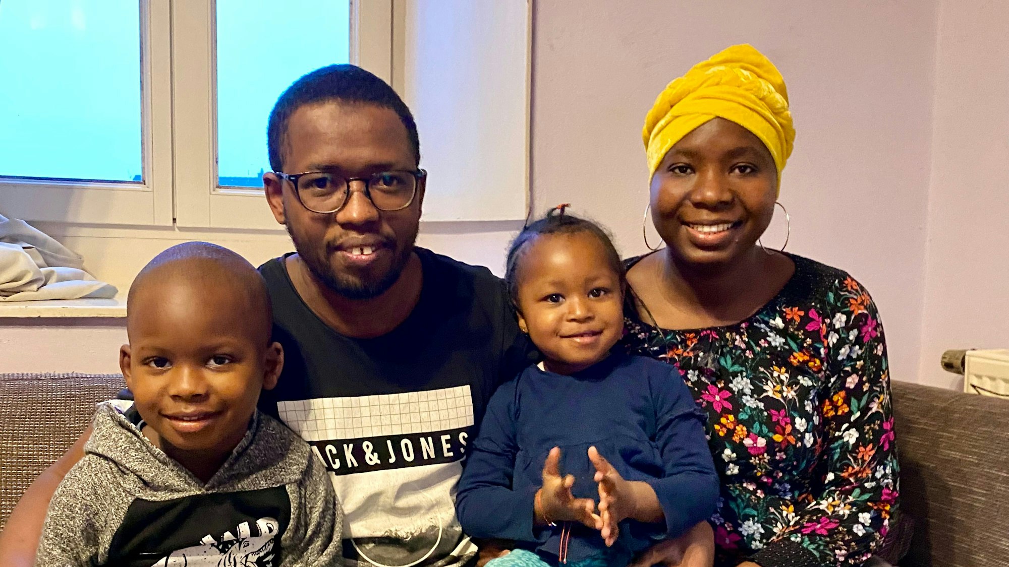 Hady Bah sitzt neben seiner Lebensgefährtin Kadiatou Diallo auf einer Couch, auf ihren Schößen die Kinder Saidou (5) und Fatima (3).