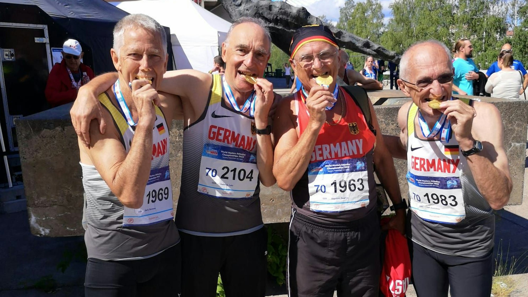 Die Sieger der 4x400-Meter-Staffel, darunter Heinrich Latz, beißen auf ihre Medaillen.