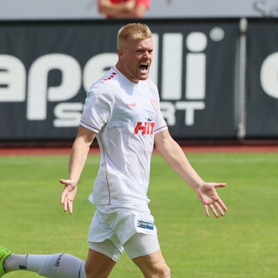 Fortuna-Stürmer Lars Lokotosch steht im Trikot auf einem Fußballplatz und jubelt.