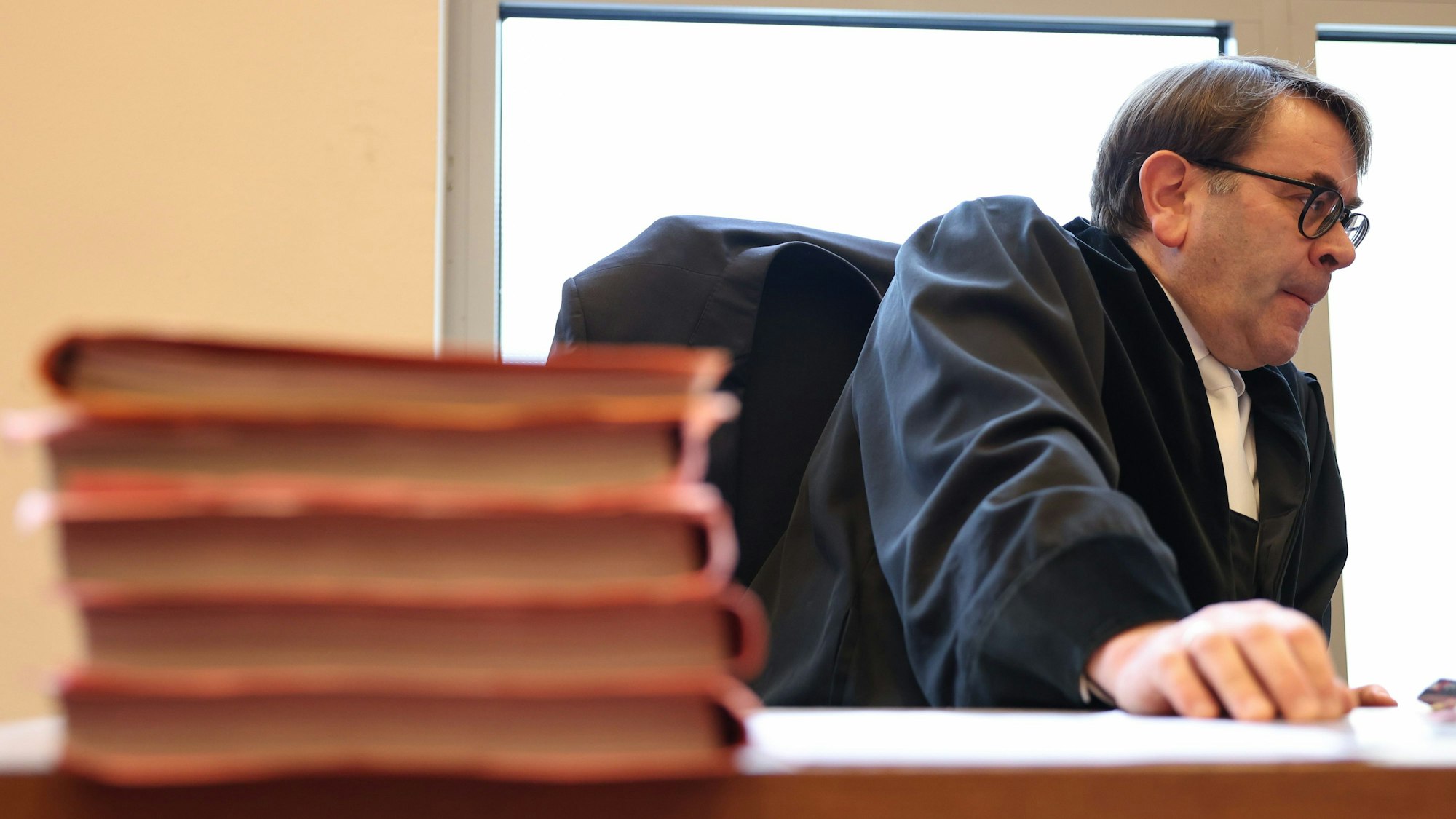 Staatsanwalt Christopher Imig sitzt in einem Saal vom Landgericht neben Prozessakten.