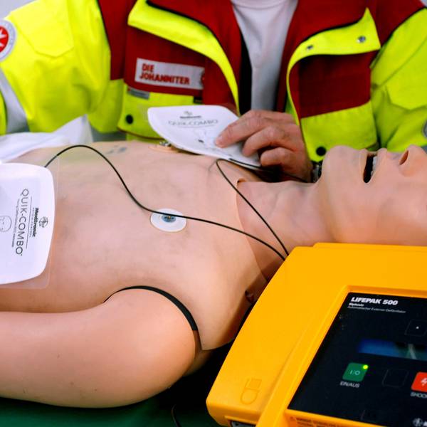 So geht’s: Ein Rettungssanitäter zeigt an einer Puppe, wie die Elektroden des Defis auf die Brust gelegt werden.