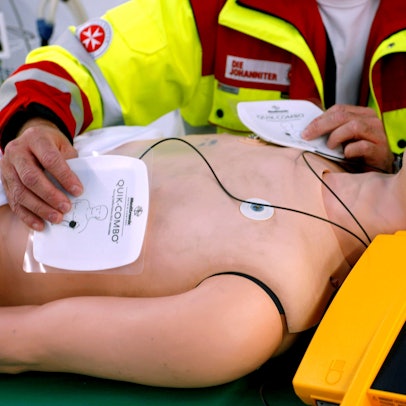 So geht’s: Ein Rettungssanitäter zeigt an einer Puppe, wie die Elektroden des Defis auf die Brust gelegt werden.