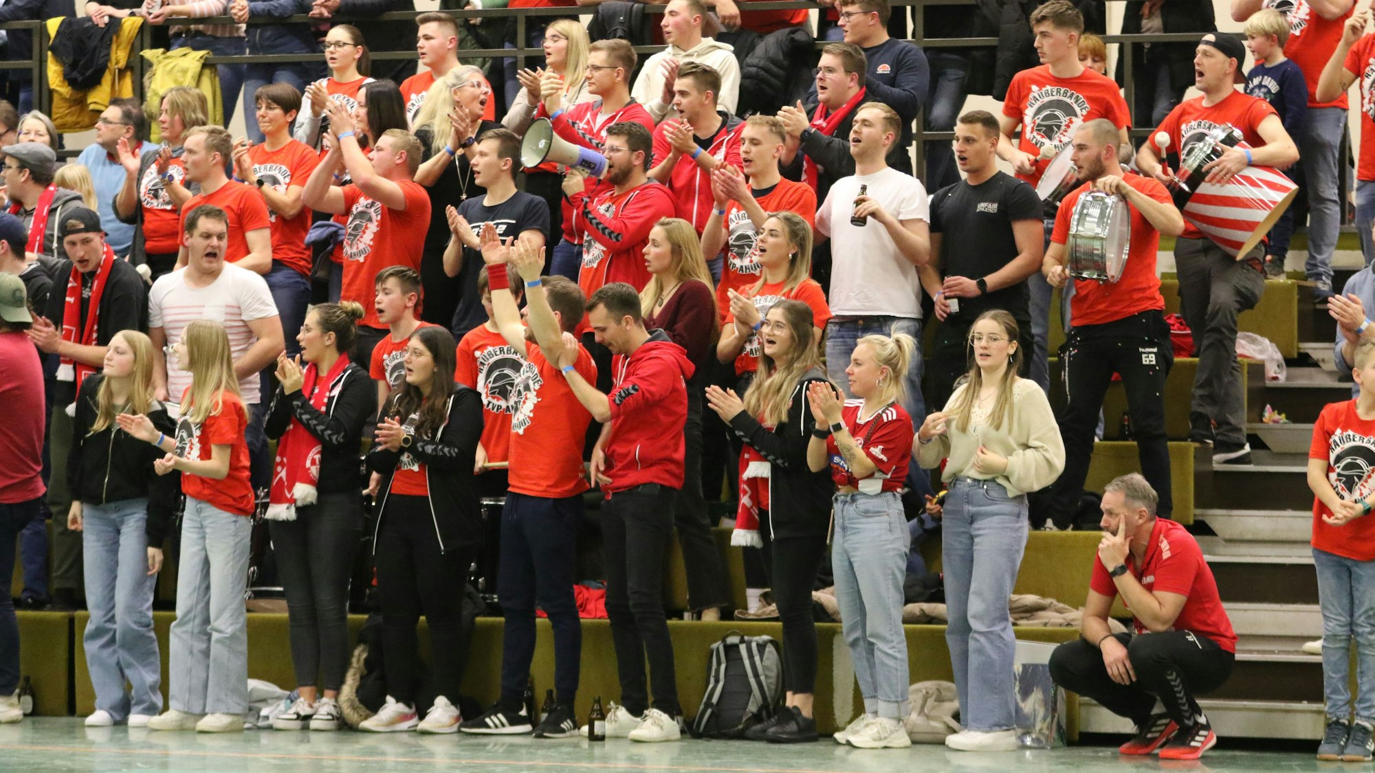 Trainer Peter Trimborn hockt nach seiner Roten Karte neben jubelnden Palmersheimer Fans.